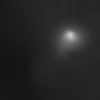 Comet 3I/ATLAS is visible as a smudgy, white speck with a diffuse halo around it against jet-black background of space. 